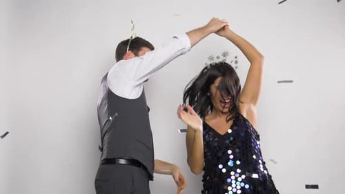 Excited couple dancing at a party with confetti