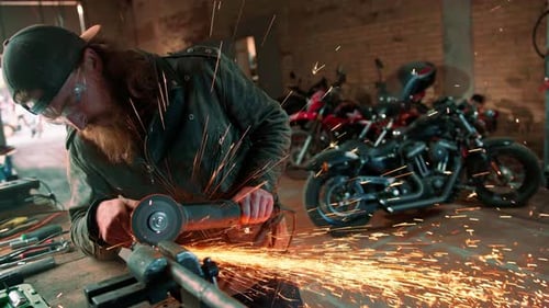 Creative authentic motorcycle workshop redhead bearded brutal biker works with circular saw Sparks