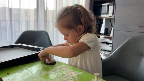 Little Girl Making Homemade Cookies Sitting at Table in Kitchen