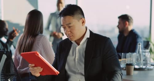 Smiling man uses tablet at office meeting