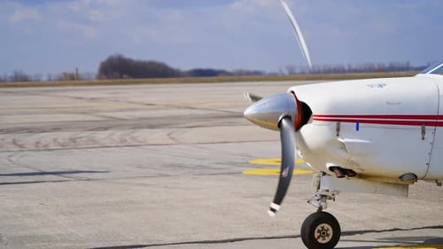 The propeller of a small white aircraft with red lines rotating.