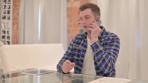 Young Man Talking on Smartphone Indoors