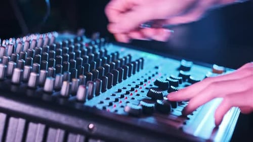 Sound Engineer Moves Faders Up and Down on Audio Mixer in Neon Light CloseUp