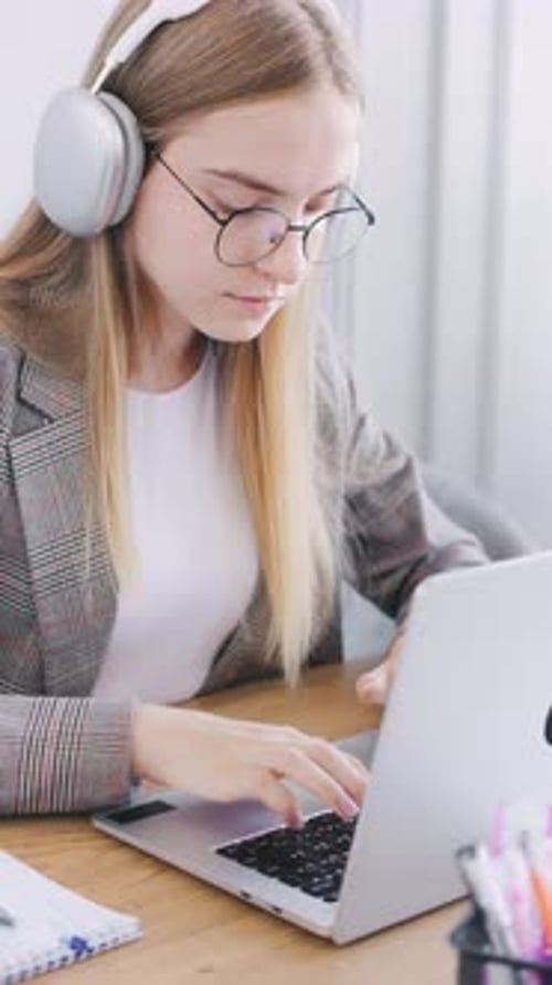 Young Woman Working on Laptop with Headphones On