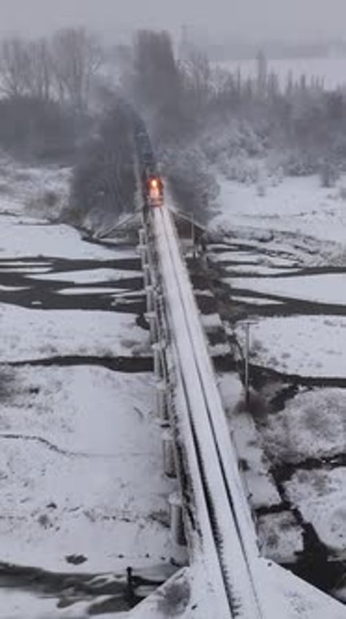 Passenger Train Crosses Snowy Bridge in Winter