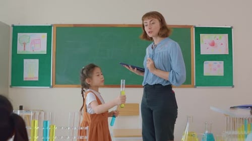 Adorable student learn with teacher in classroom at elementary school.