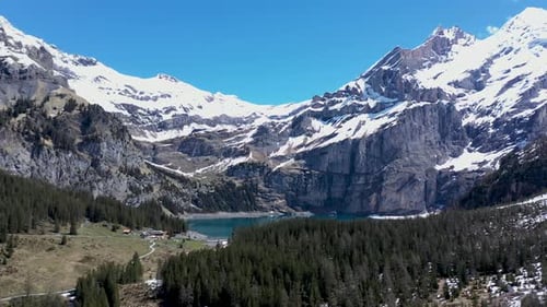 Drone flight over a beautiful alpine glacier valley, lake and vast mountainous landscape. Kandersteg