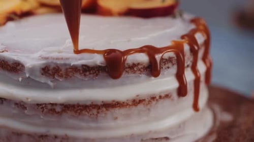 Cake Decoration - Pastry Chef Squeezing Caramel Icing On A Round Cake. - close up shot