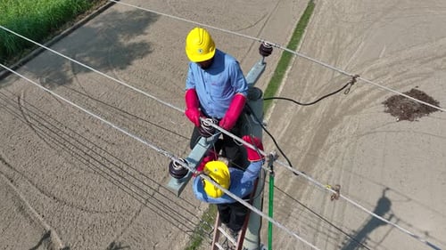 Aerial view of linemen on utility pole, Bangladesh.