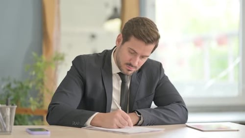 Young Adult Writes at Desk in an Office