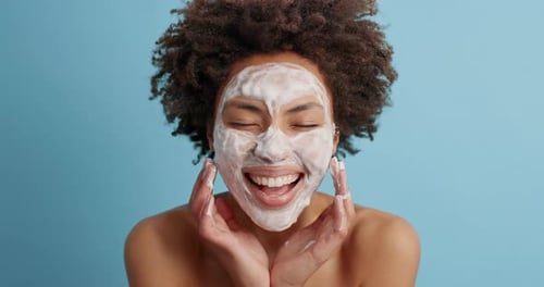 Woman with Face Mask Smiling Against Blue Background