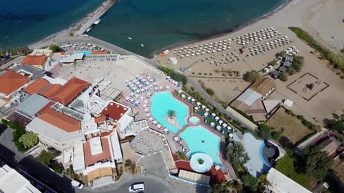 Drohne fliegt über das Strandresort mit Blick auf Pool und Strand in Griechenland auf Kreta, Sonnenschirme am Strand