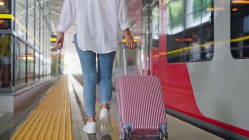 Woman Pulling Luggage on Train Platform