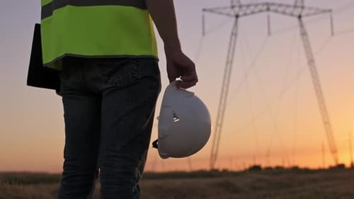 White safety helmet in hands of male electrician engineer worker close-up against background