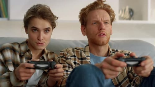 Couple plays video games at home on couch