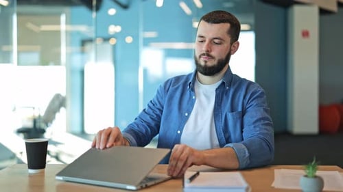 Happy Professional Man Finishes Work on Laptop in Modern Office