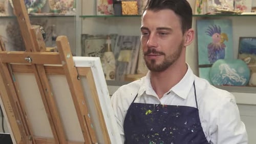 Handsome Bearded Male Artist Passionately Painting in His Vibrant Art Studio