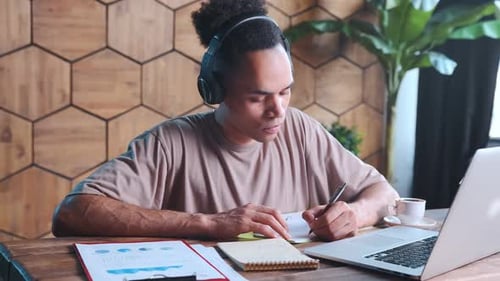 Young Adult Wearing Headphones Working at Laptop