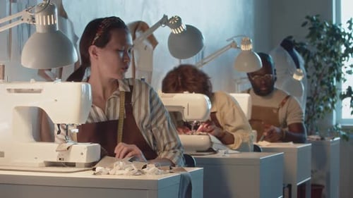 Verschiedene Schneider arbeiten in einer Bekleidungsfabrik an Nähmaschinen
