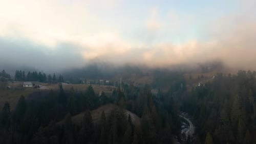 View From Above of Vibrant Landscape of Foggy Clouds Covering Mountain Hills and Village Houses at