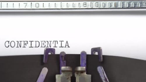 Confidential word closeup being typing and centered on a sheet of paper on old vintage typewriter