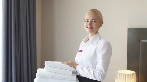 Hermosa sirvienta con ropa blanca y toallas en sus manos