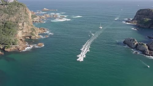 Aerial View Of Boats Navigating Through Rugged Coastal Rock Formations