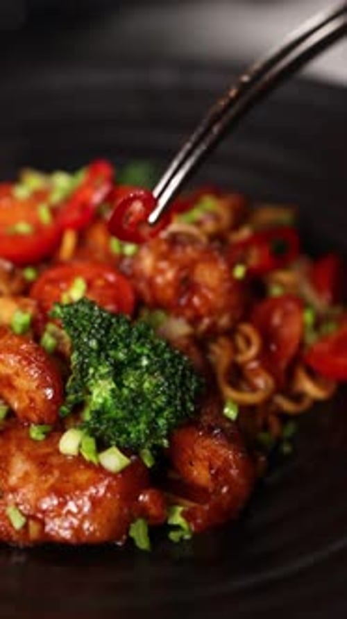 Red Pepper Ring Being Placed on Noodles