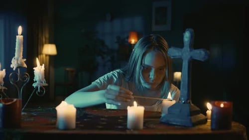 Woman Lights Incense Reading by Candlelight Indoors
