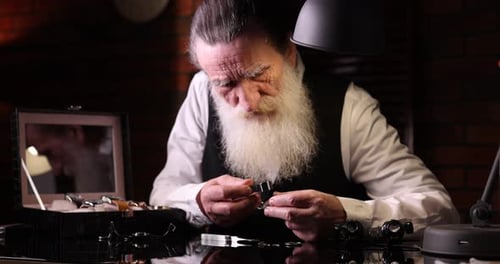 Senior man fixing mechanism of vintage wrist watch at black mirror table indoors