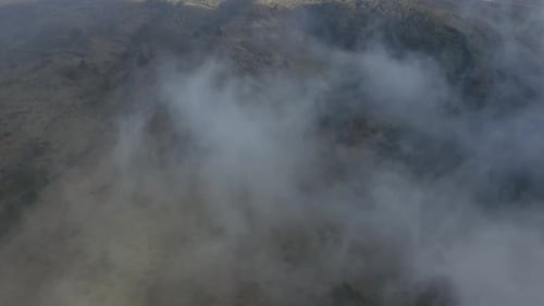 Drone dolly view of white clouds revealing the slopes of Haleakala volcano on Maui, Hawaii.