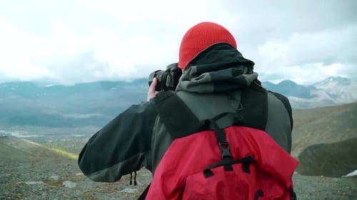 Traveler takes pictures with camera of mountain landscape with clouds