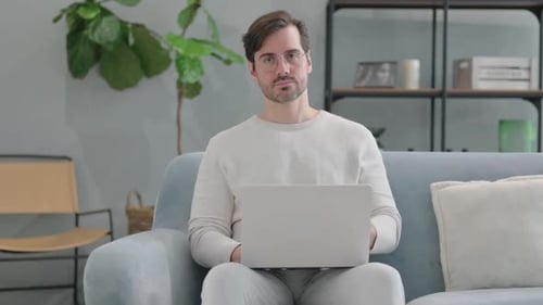 Man Using Laptop and Massaging Neck Indoors