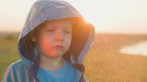 Child in Raincoat in Gentle Rain at Sunset