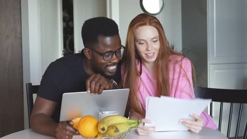 Young Adults Reviewing Documents at Home Together