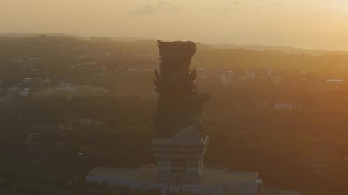 Silhouette latérale de Garuda Wisnu Kencana sur un horizon lumineux au coucher du soleil