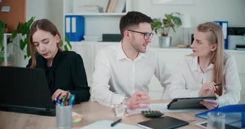 Businesswoman Using Laptop By Colleagues Discussing in Office