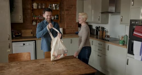 Couple unpacking groceries in bright modern kitchen interior