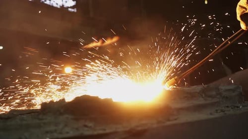Worker Welding Metal with Flying Sparks in Factory