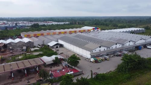Aerial view of a goods distribution warehouse lined up with goods trucks parked in front of the ware