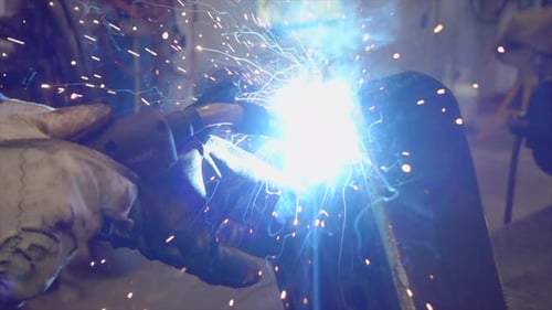 Gloved Hands Welding Metal with Dazzling Sparks