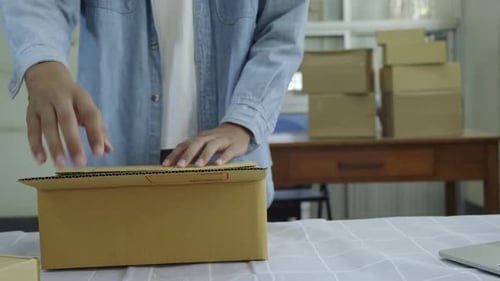Person Packing Item Into a Box at Home