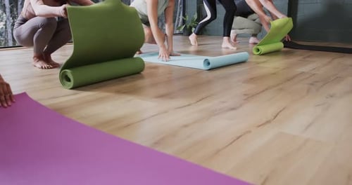Women Unrolling Yoga Mats on Studio Floor