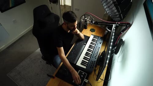 Musician Composes and records music. Playing piano in home sound studio Wide top shot.