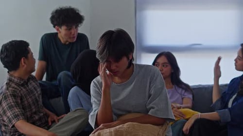 Quiet man experiencing social anxiety and emotional discomfort while surrounded lively crowd indoors
