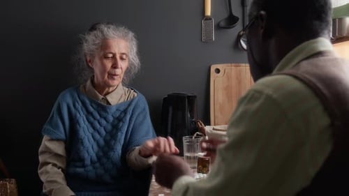 Senior Woman Taking Medication with Water in Kitchen