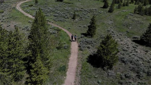 Drone footage of man and woman hiking on a trail.