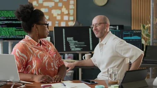 Multiethnic Software Engineers Discussing Work in Modern Open Space Office