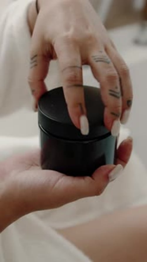 Hand Takes Exfoliating Scrub From Black Jar