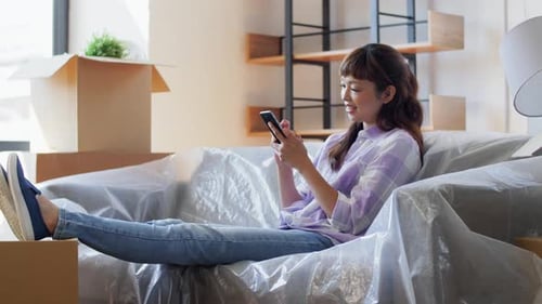 Woman relaxes using phone in new house